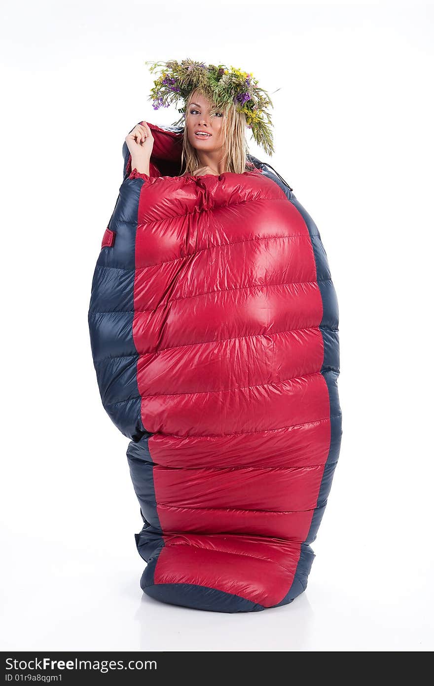 Young blonde woman with the wraest on her head in the down sleeping bag. Young blonde woman with the wraest on her head in the down sleeping bag