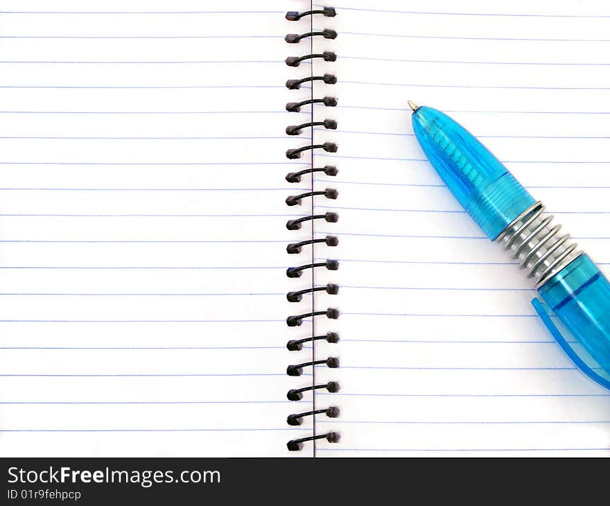 A blue pen on an empty open notepad. A blue pen on an empty open notepad.