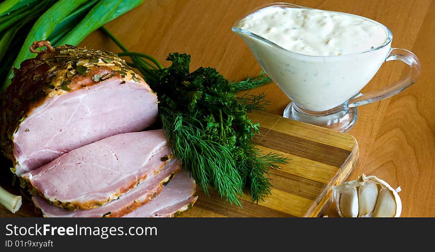 Slices of ham, potherbs and salad of green vegetables on the kitchen table. Slices of ham, potherbs and salad of green vegetables on the kitchen table