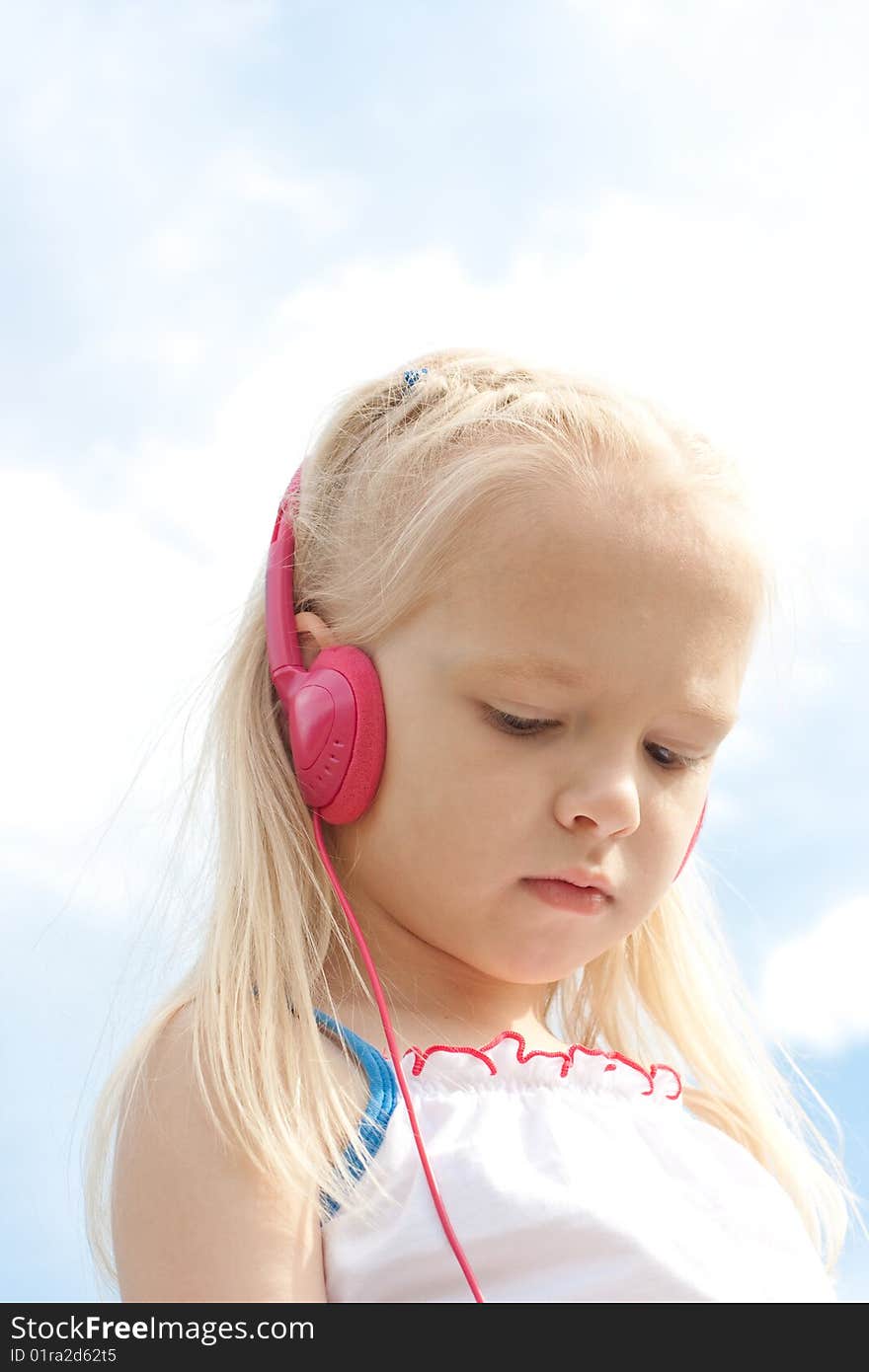 Little blonde girl with closed eyes in red earphones listens mp3 player music outdoor. Little blonde girl with closed eyes in red earphones listens mp3 player music outdoor