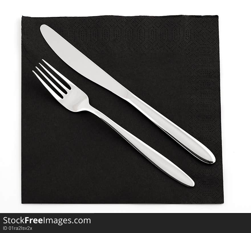 Fork and knife on a black napkin, isolated on a white background. Fork and knife on a black napkin, isolated on a white background