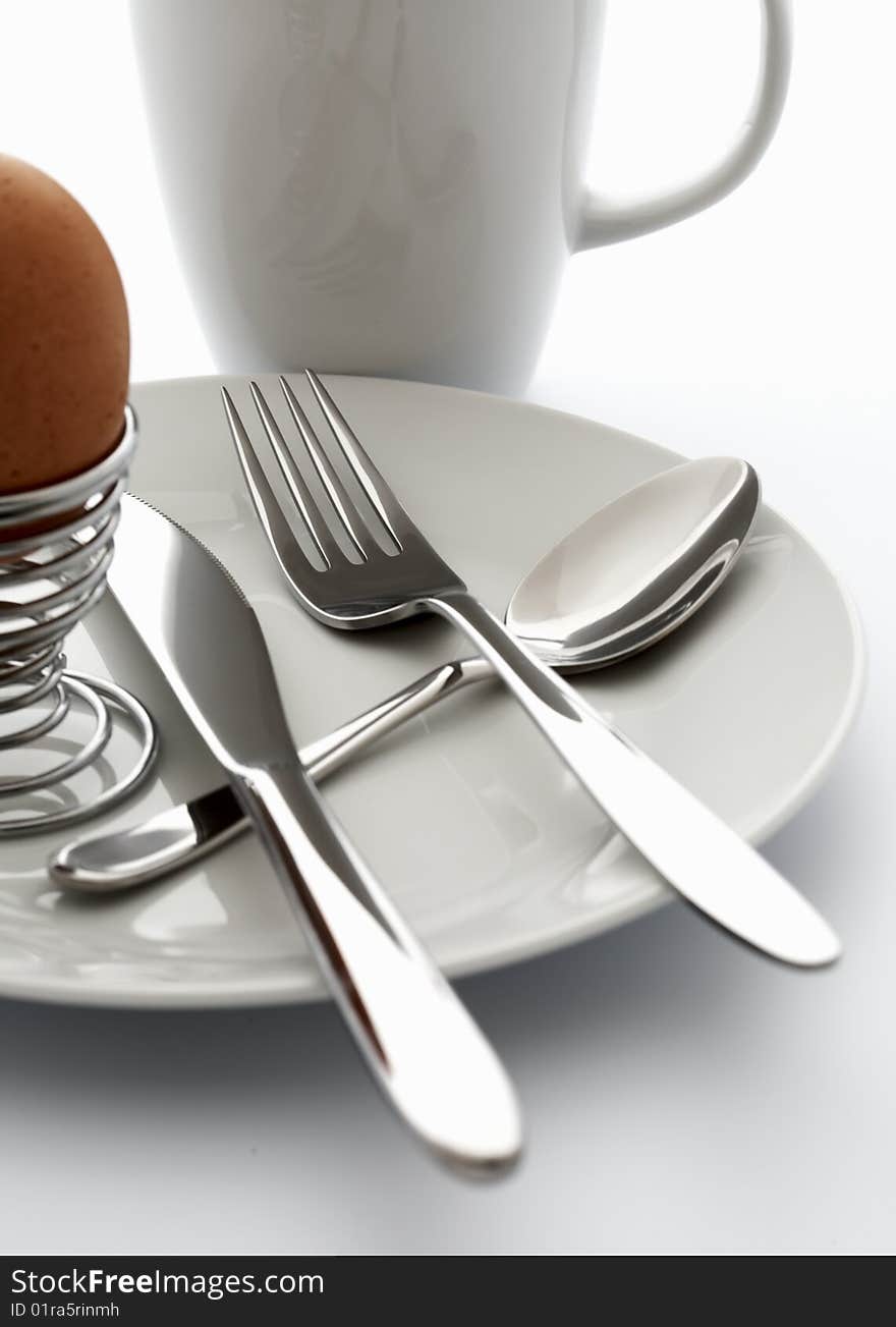 Silver cutlery and an egg on a white plate. Silver cutlery and an egg on a white plate