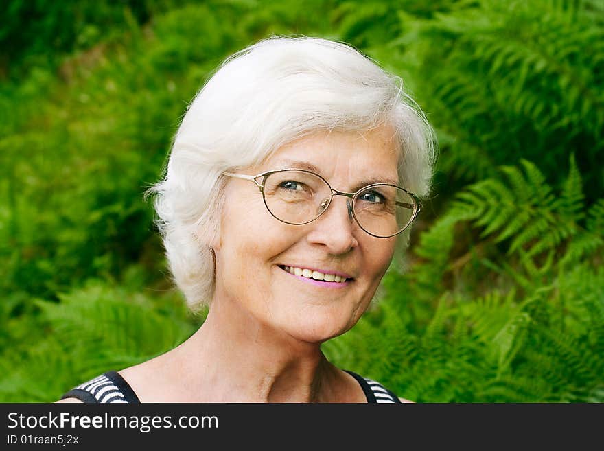 Senior woman portrait, outdoor, in front of fern,smiling to camera. Senior woman portrait, outdoor, in front of fern,smiling to camera