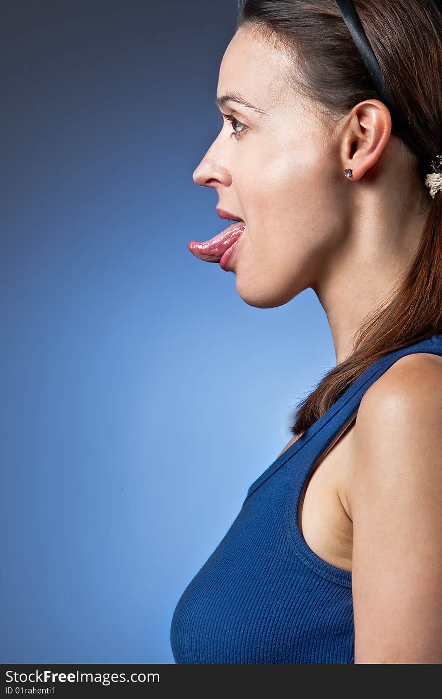 A young woman poking out her tongue in profile. A young woman poking out her tongue in profile.