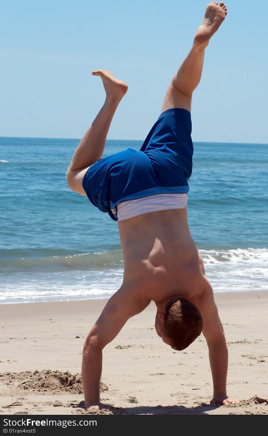 Man standing on his arms at the beach. Man standing on his arms at the beach