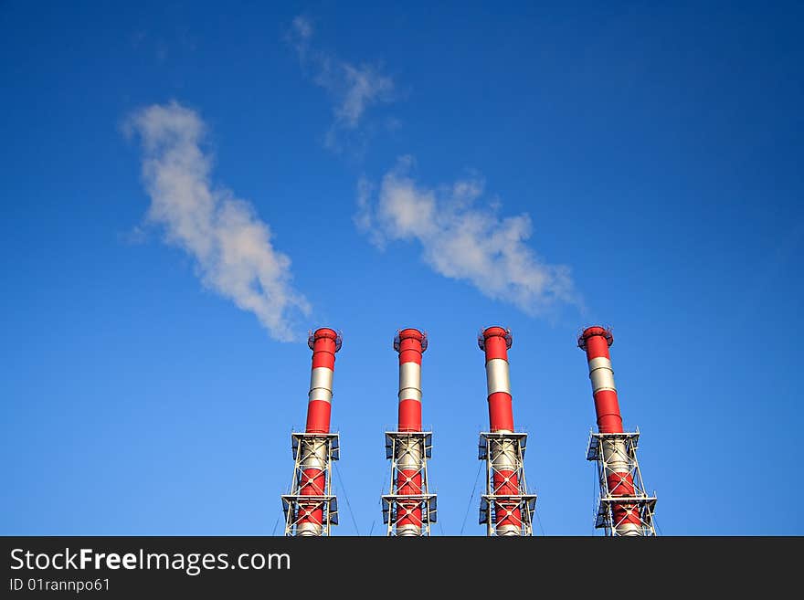 Four factory chimney smoking  on a background blue Sky