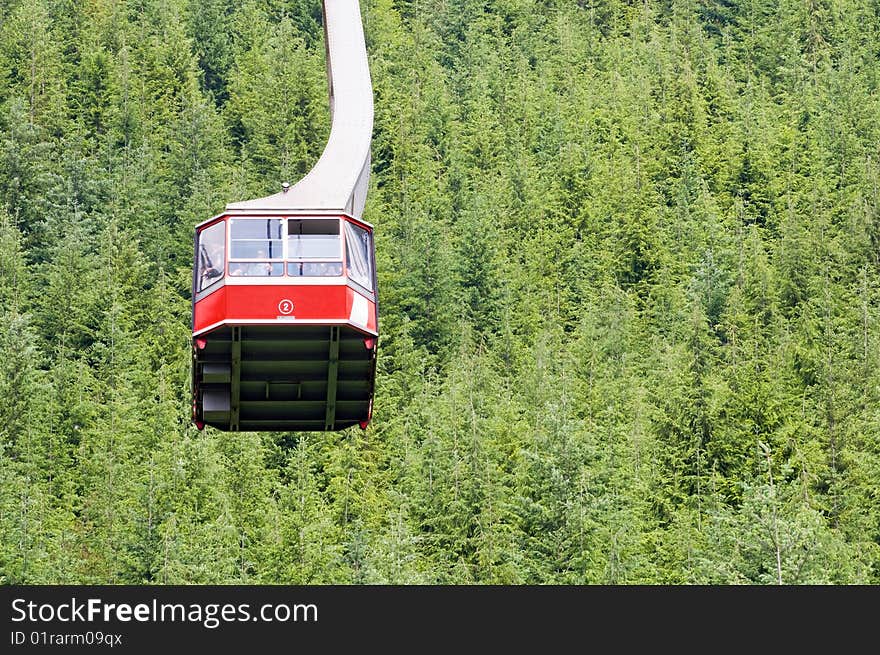 A view of a cable car or gondola suspended over a forested mountainside. A view of a cable car or gondola suspended over a forested mountainside.