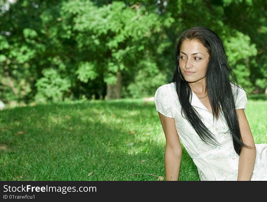 Pretty girl in a park sitting down and smiling. Pretty girl in a park sitting down and smiling