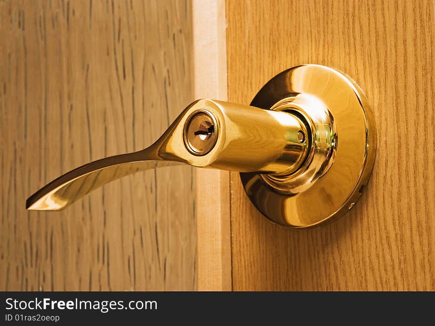 Shiny metal knob with a lock and key in a wooden door. Shiny metal knob with a lock and key in a wooden door