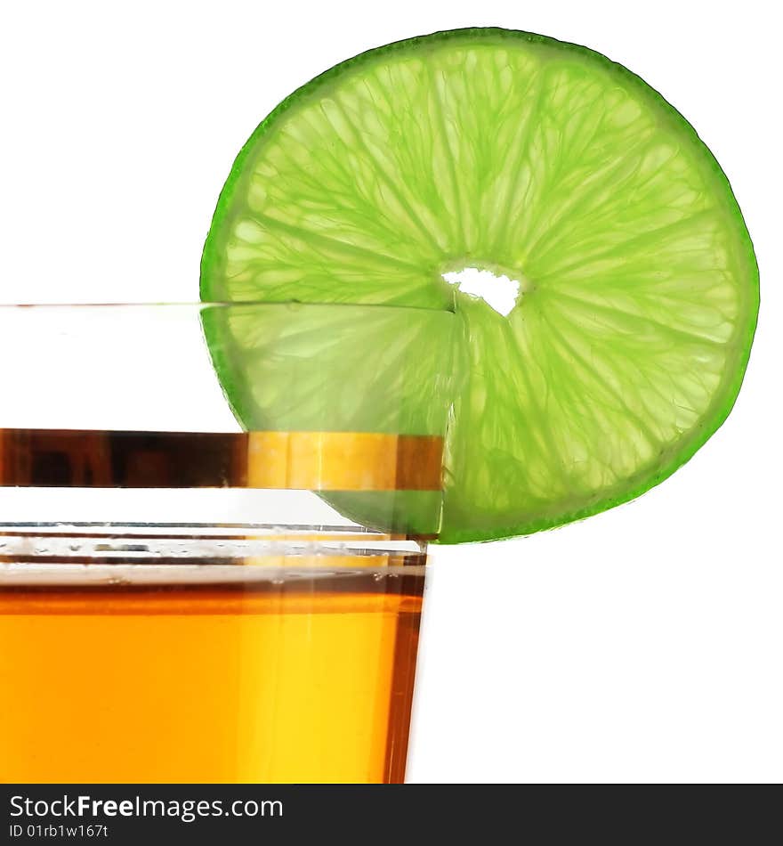 Lime green slice on edge of glass with juice