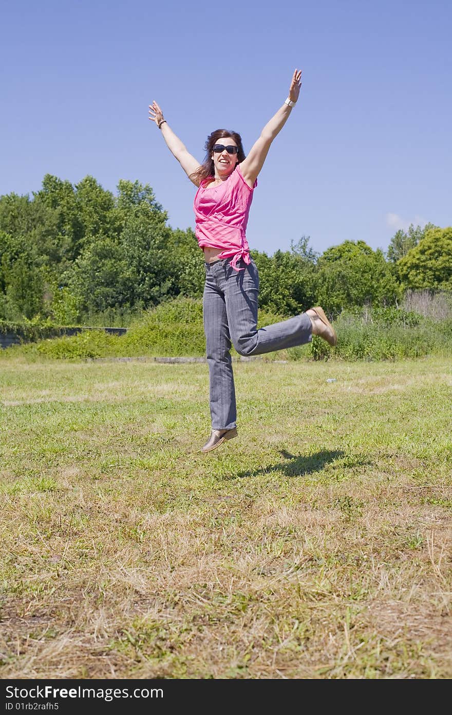 A young woman is jumping on an open field. A young woman is jumping on an open field