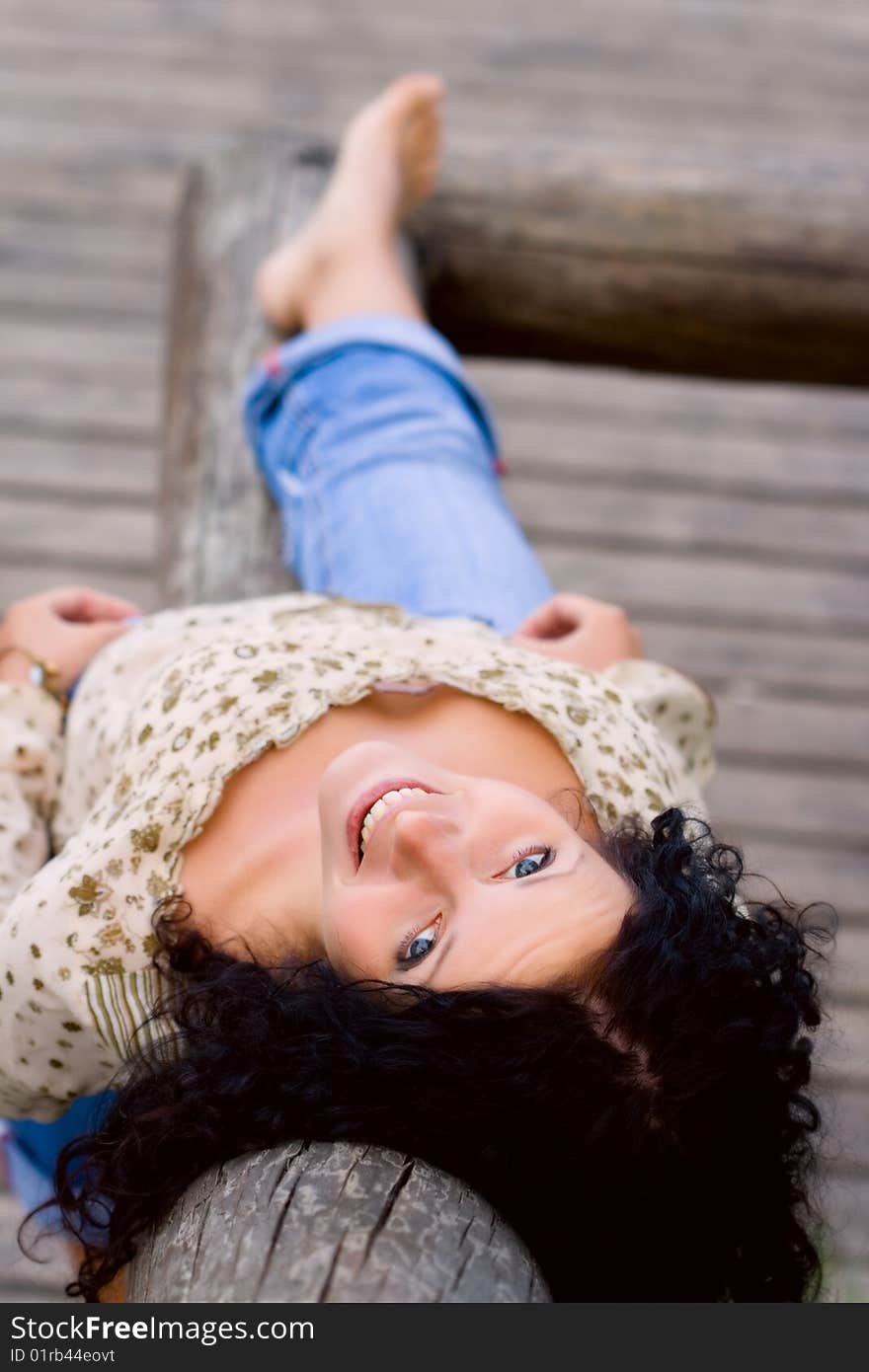 Outdoor portrait of beautiful brunet woman lying on wooden floor