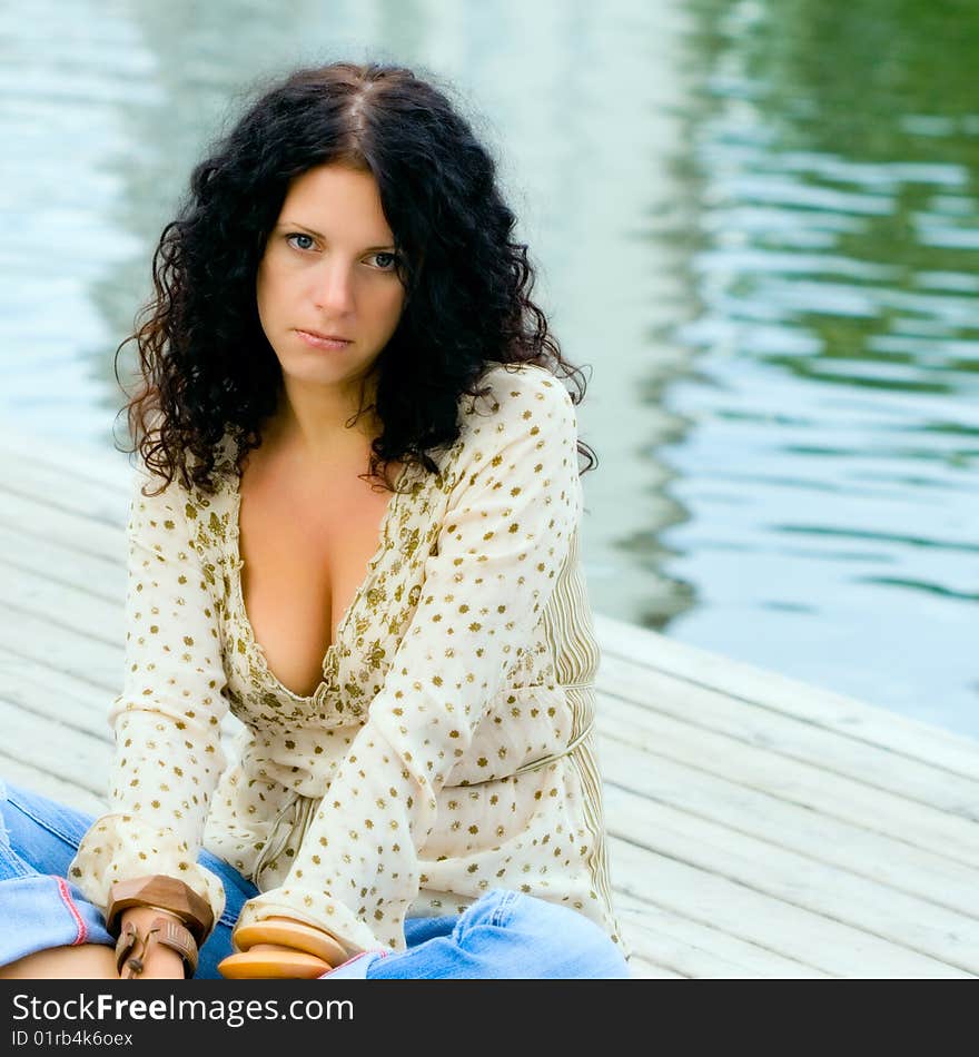 Beautiful unhappy woman sitting near the water