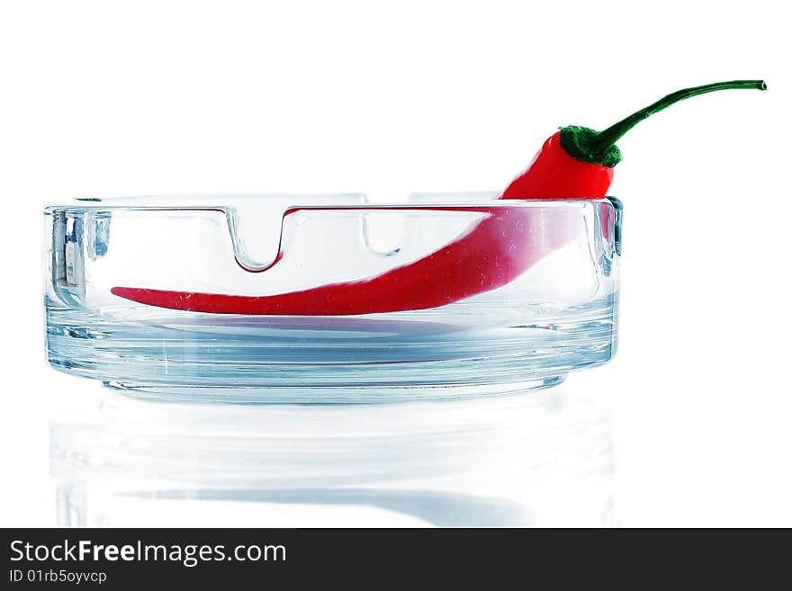 Red chili pepper on glass ashtray isolated on white