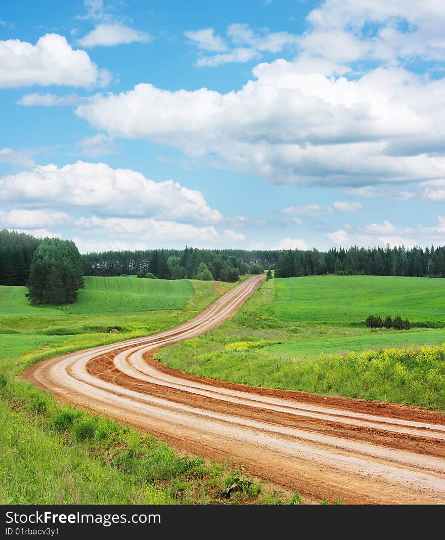 Rural double side road with green lawn and blue sky with clouds