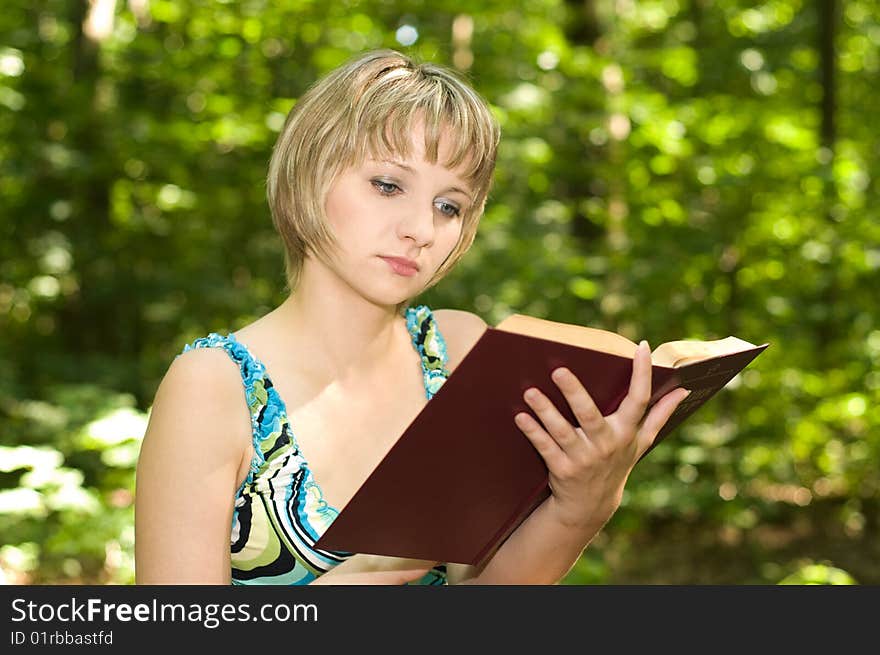 Beautiful student girl reading book in the park