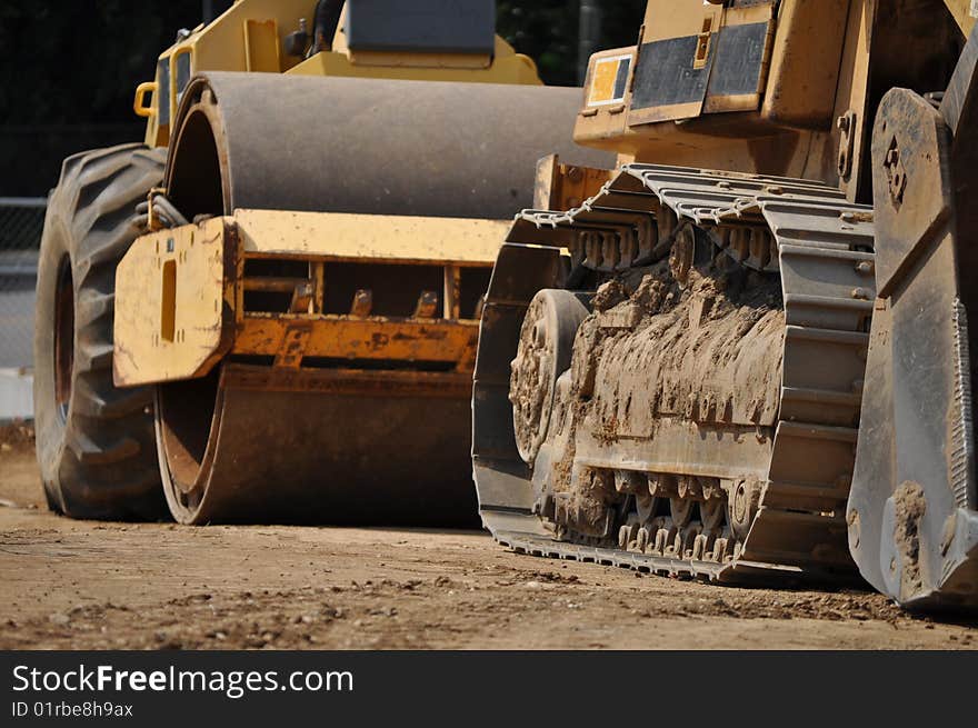 Two yellow construction vehicles sit in line with each other on a jobsite. Two yellow construction vehicles sit in line with each other on a jobsite.