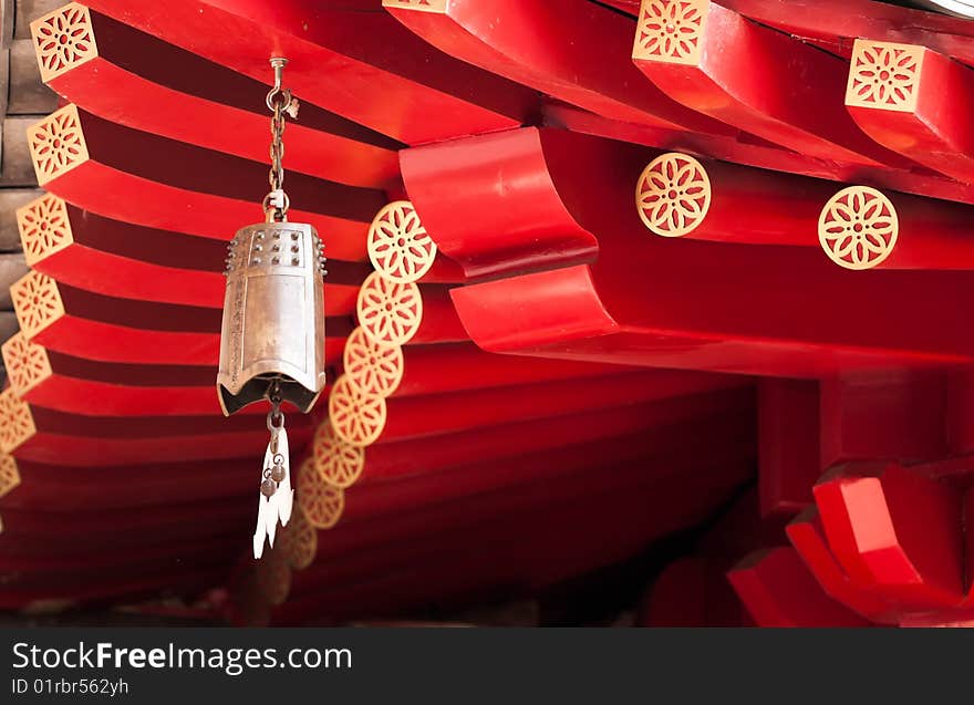 A brass bell with a bat shaped clapper hanging at the corner of the roof of a Buddhist temple build in classical Chinese architectural style, in Chinatown, Singapore. A brass bell with a bat shaped clapper hanging at the corner of the roof of a Buddhist temple build in classical Chinese architectural style, in Chinatown, Singapore