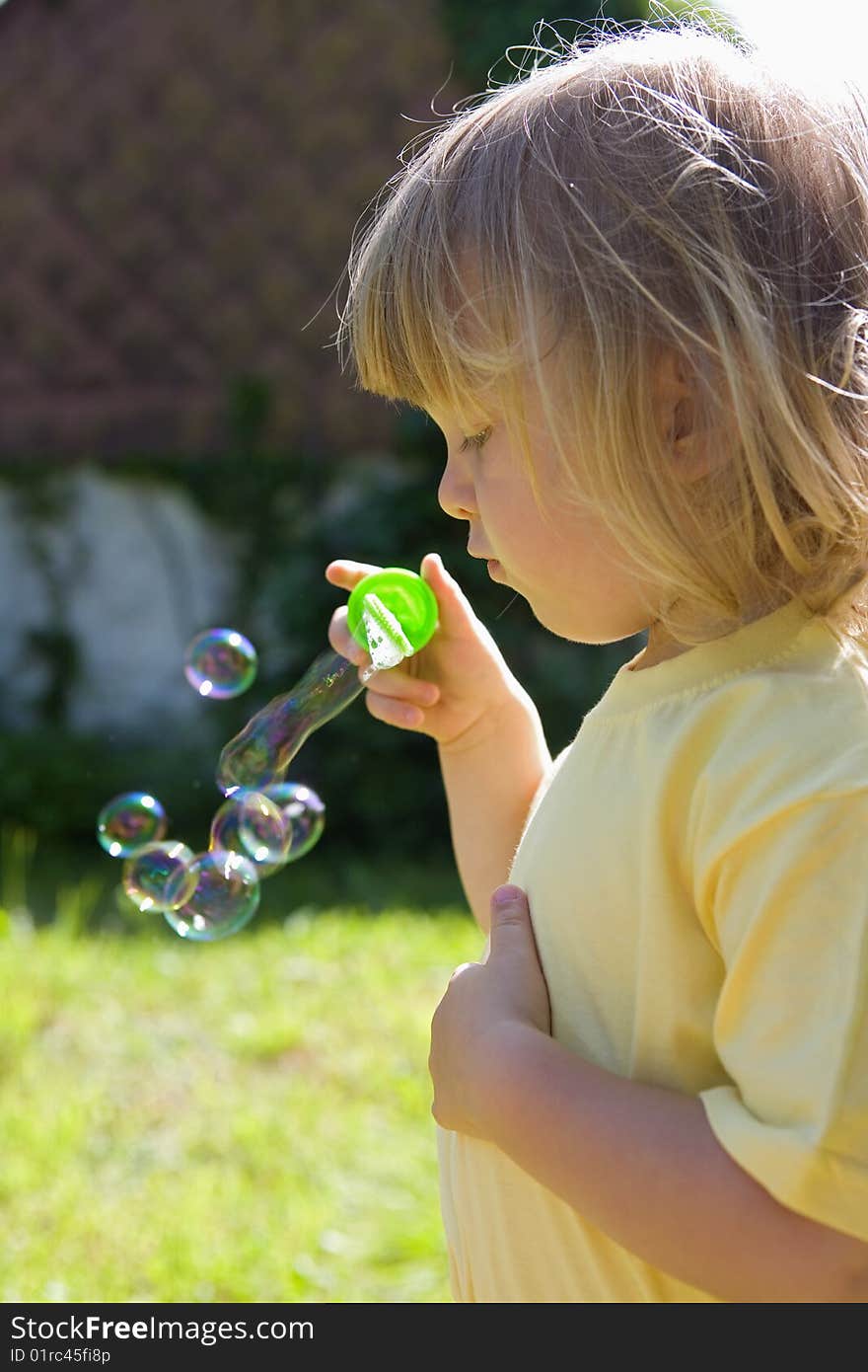 Boy with long blond hair blowing soap bubbles outdoors. Boy with long blond hair blowing soap bubbles outdoors