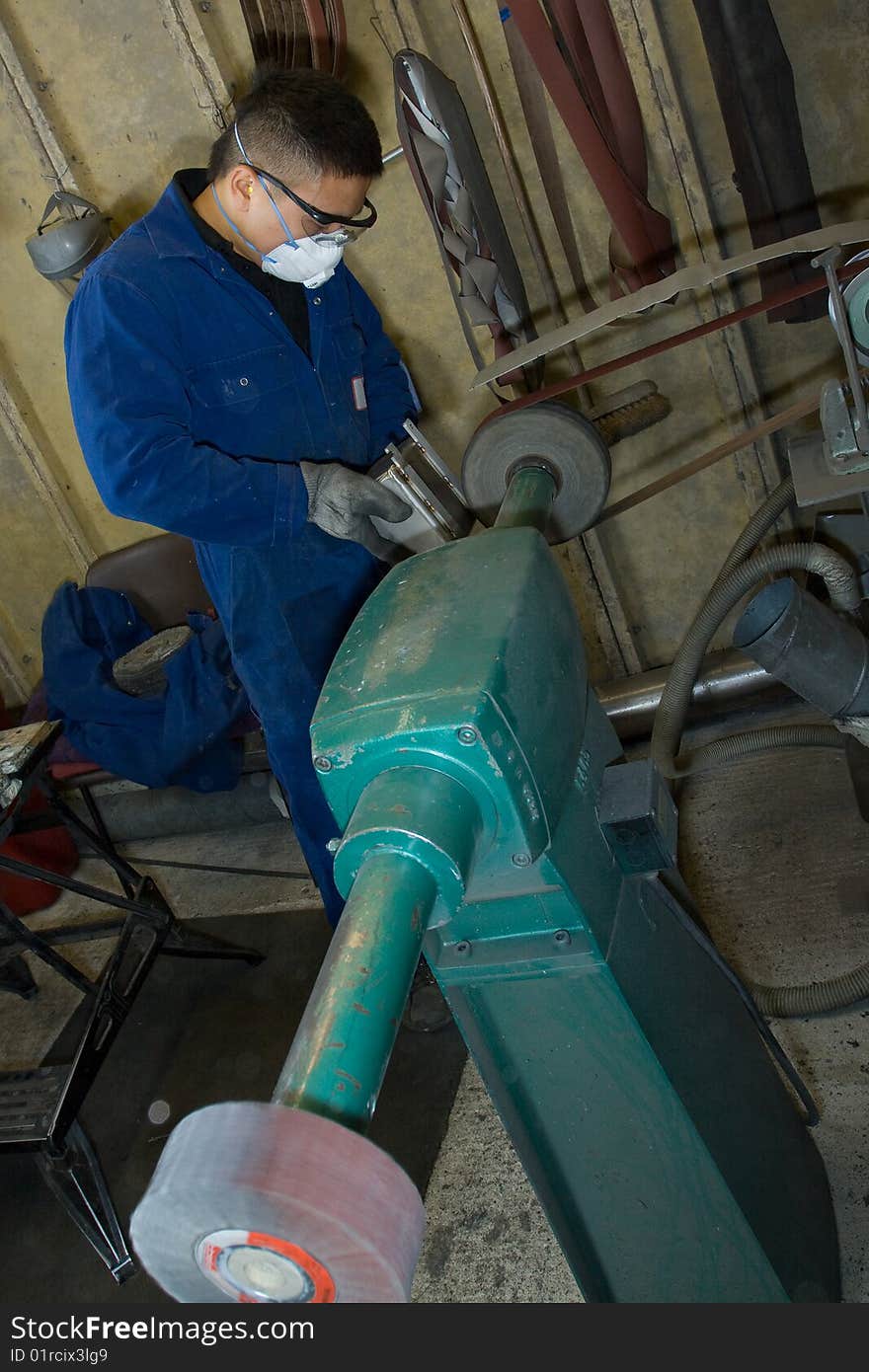 Man using electric polisher on stainless steel box in workshop. Man using electric polisher on stainless steel box in workshop