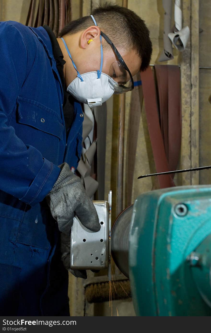 Man using electric polisher on stainless steel box in workshop. Man using electric polisher on stainless steel box in workshop