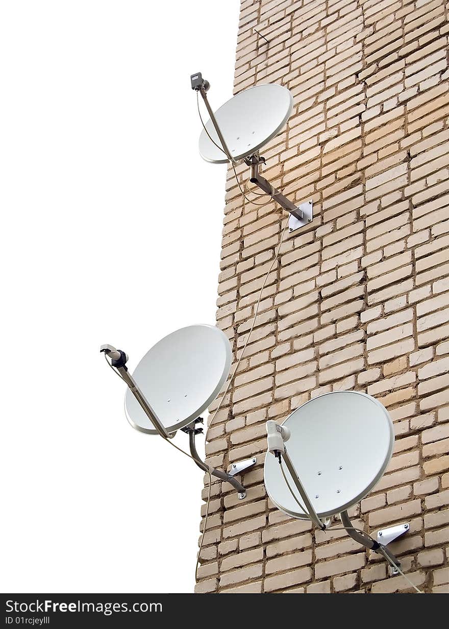 Three satellite antennas on the home front on the background wall of bricks