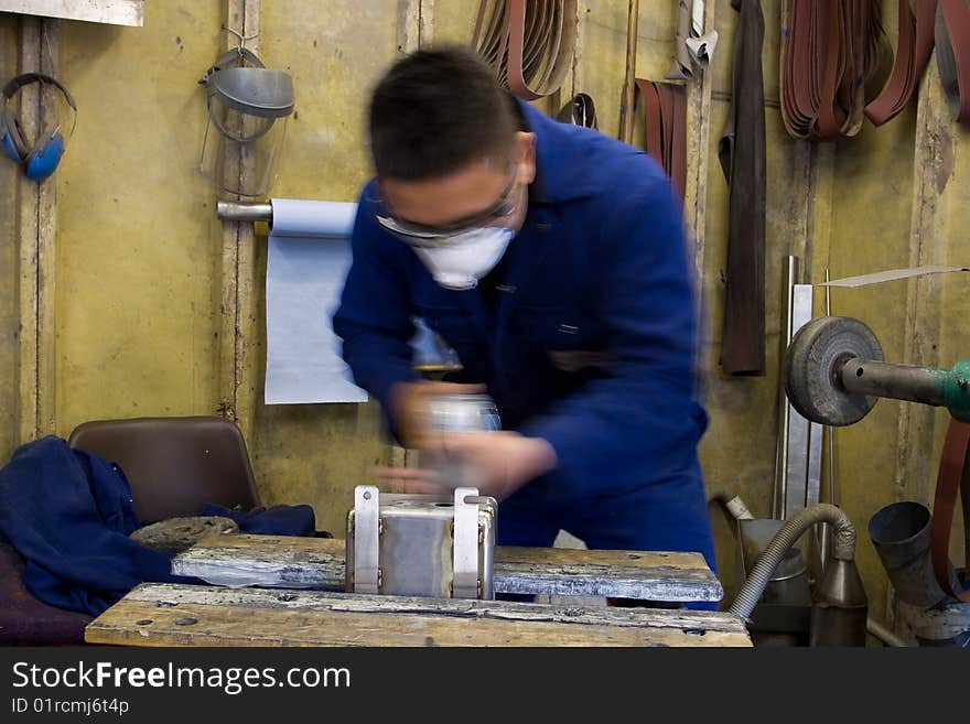 Man using electric polisher on stainless steel box in workshop. Man using electric polisher on stainless steel box in workshop