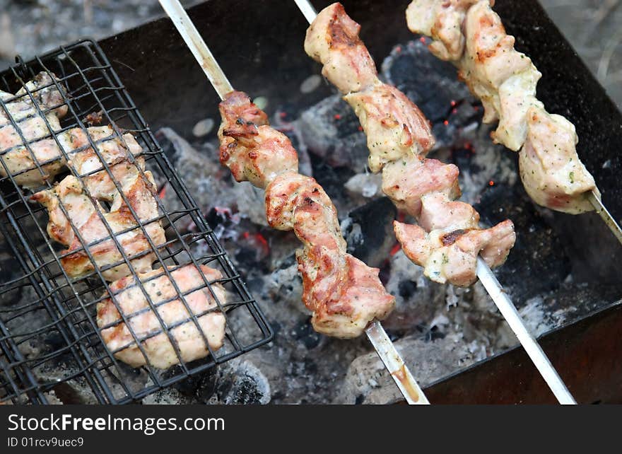 Shish kebab roasting on an open fire to background