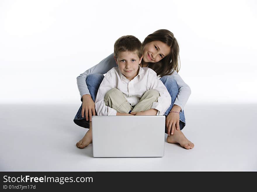 Studio shot on white background of two pretty children sitting together with a laptop computer. Studio shot on white background of two pretty children sitting together with a laptop computer