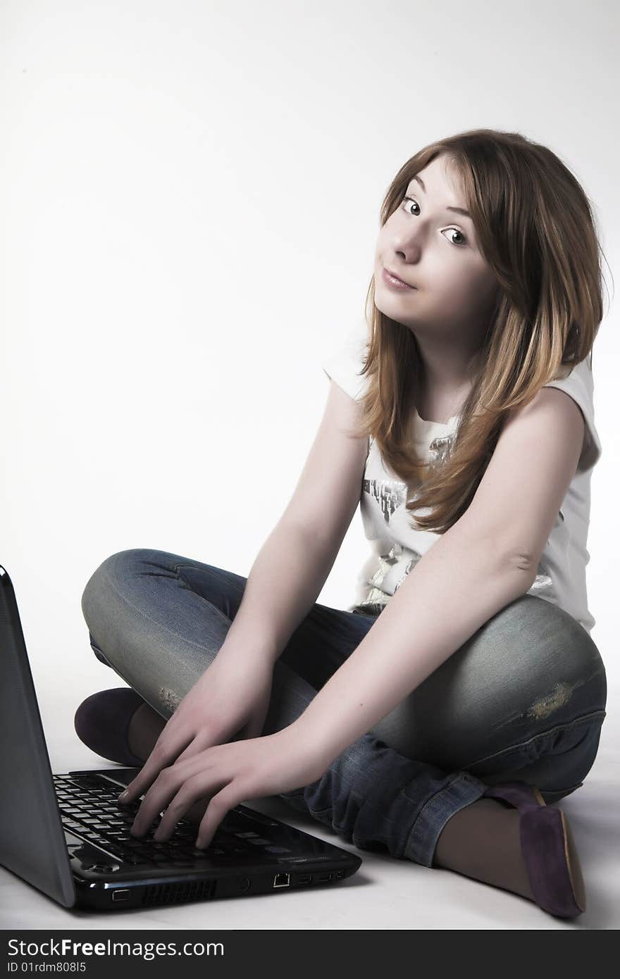 Casual teenage girl on a laptop on a white background working on the floor