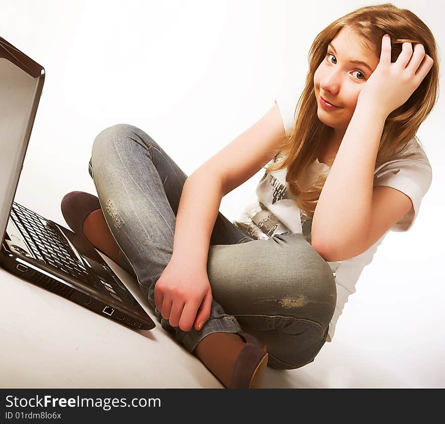 Casual teenage girl on a laptop on a white background working on the floor