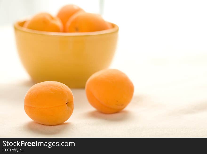 Apricots in yellow bowl on linen table cloth wrinked to show texture at low depth of field