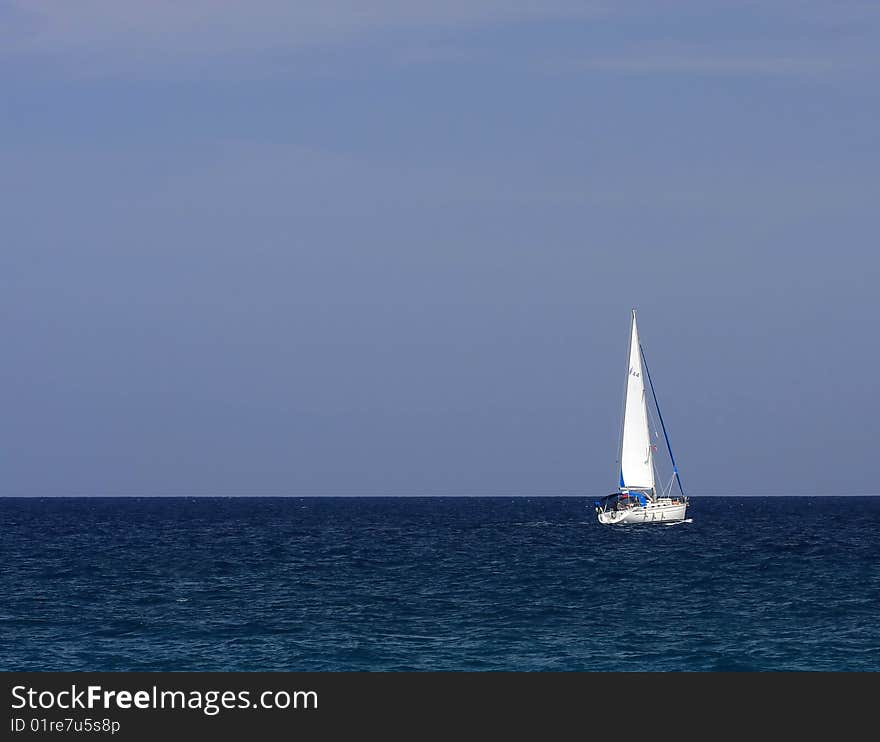 White sailboat floating on the blue sea