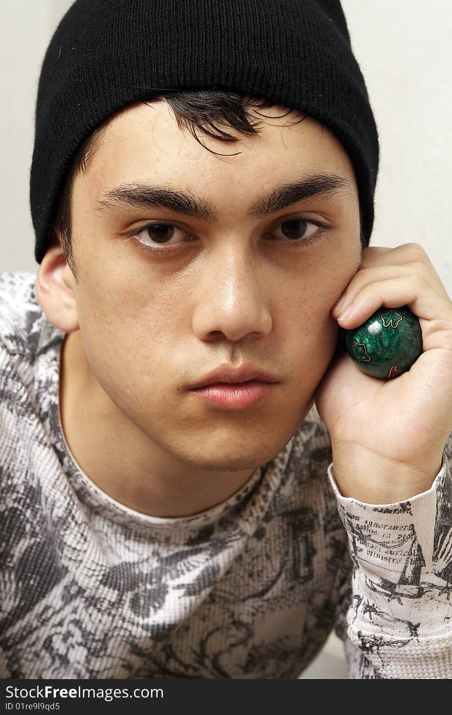 A young man sitting down holding two green chinese stress balls. A young man sitting down holding two green chinese stress balls.