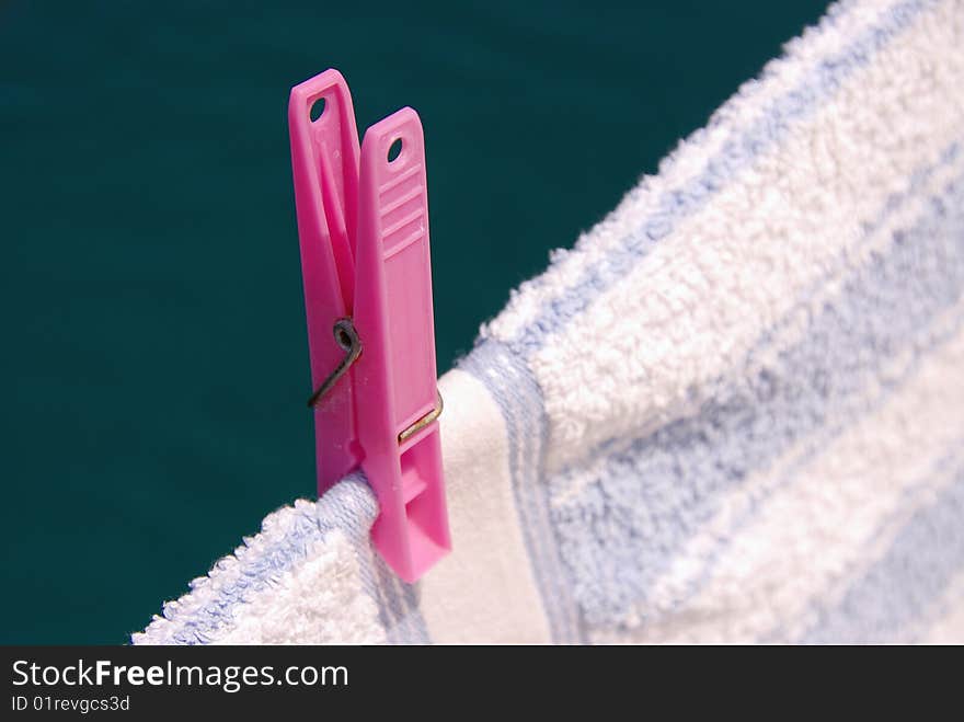 A pink clothespin at a towel. A pink clothespin at a towel