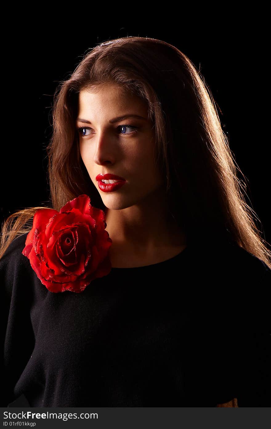 Portrait of a young beautiful brunettes with red lips in a black blouse decorated with a rose. Portrait of a young beautiful brunettes with red lips in a black blouse decorated with a rose