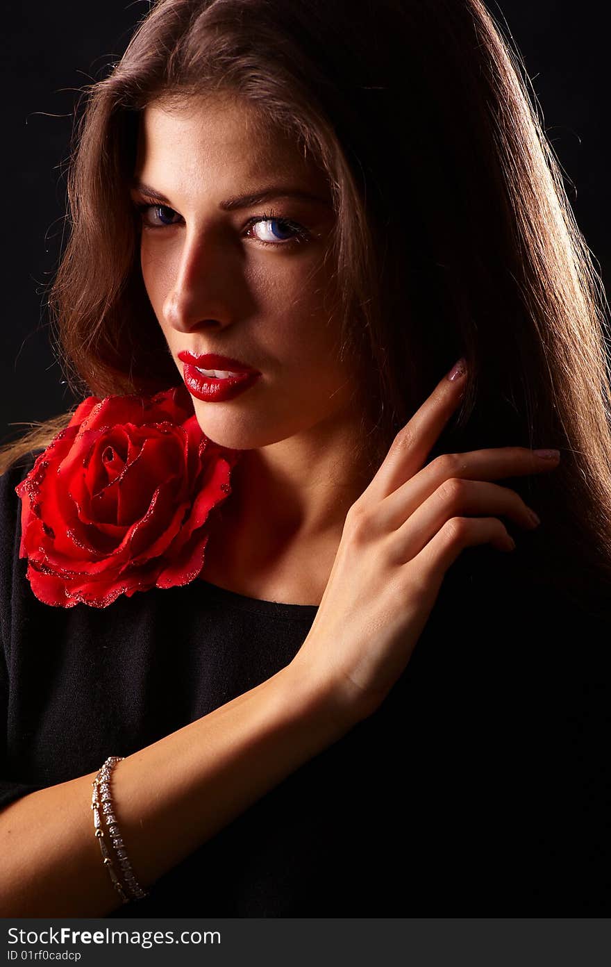 Portrait of a young beautiful brunettes with red lips in a black blouse decorated with a rose. Portrait of a young beautiful brunettes with red lips in a black blouse decorated with a rose