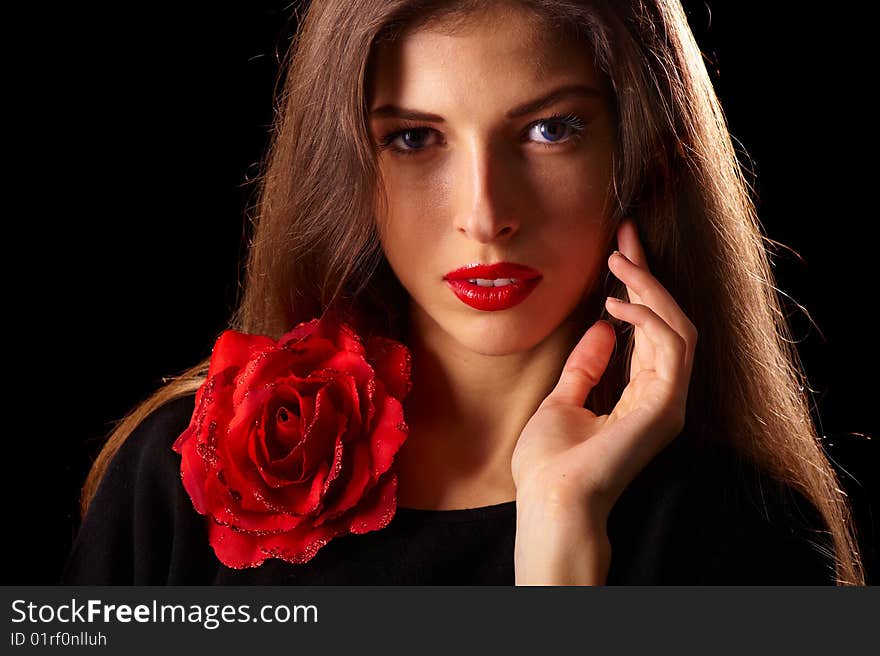 Portrait of a young beautiful brunettes with red lips in a black blouse decorated with a rose. Portrait of a young beautiful brunettes with red lips in a black blouse decorated with a rose