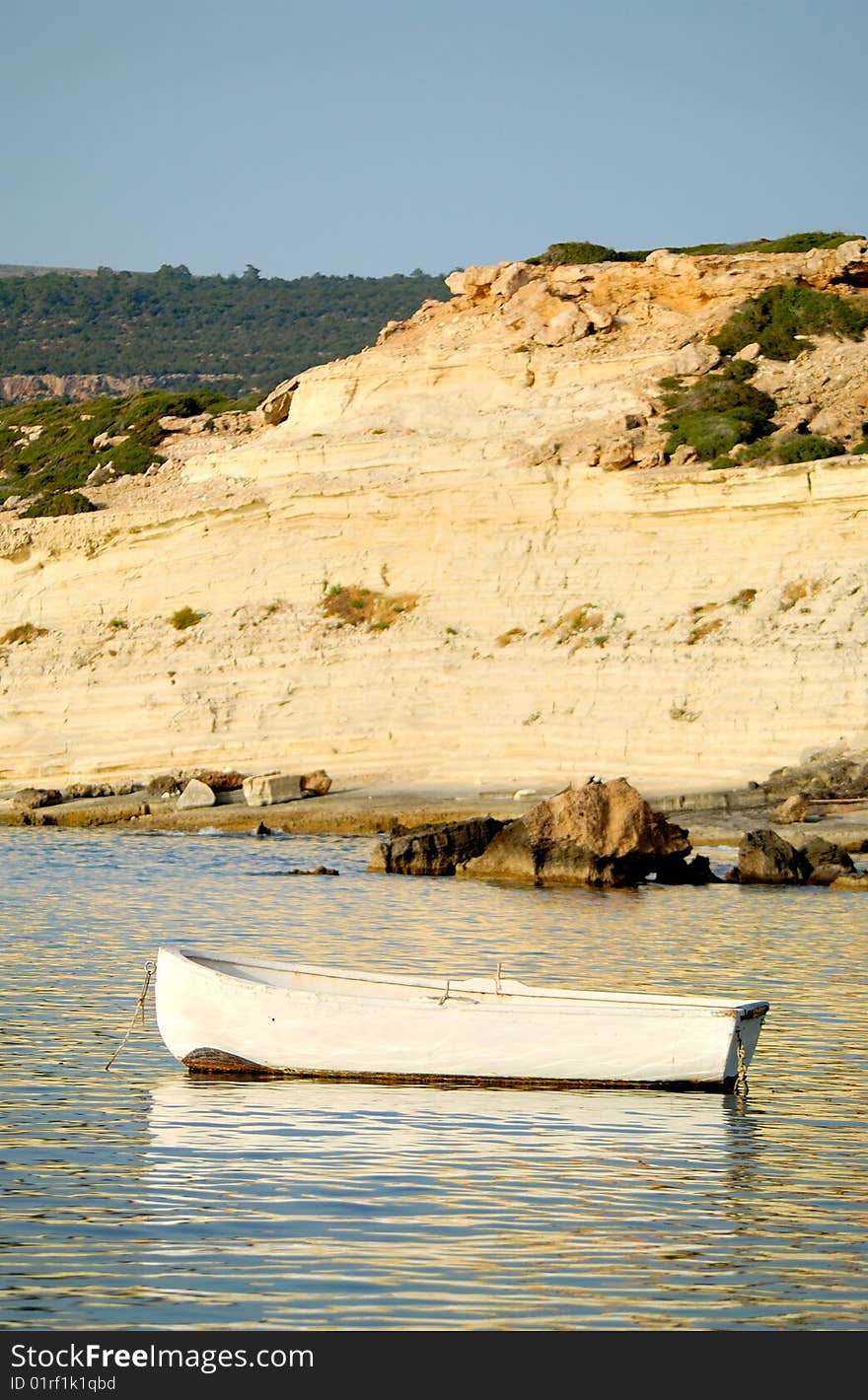 A white shallop in the sea near rocky coast. A white shallop in the sea near rocky coast.