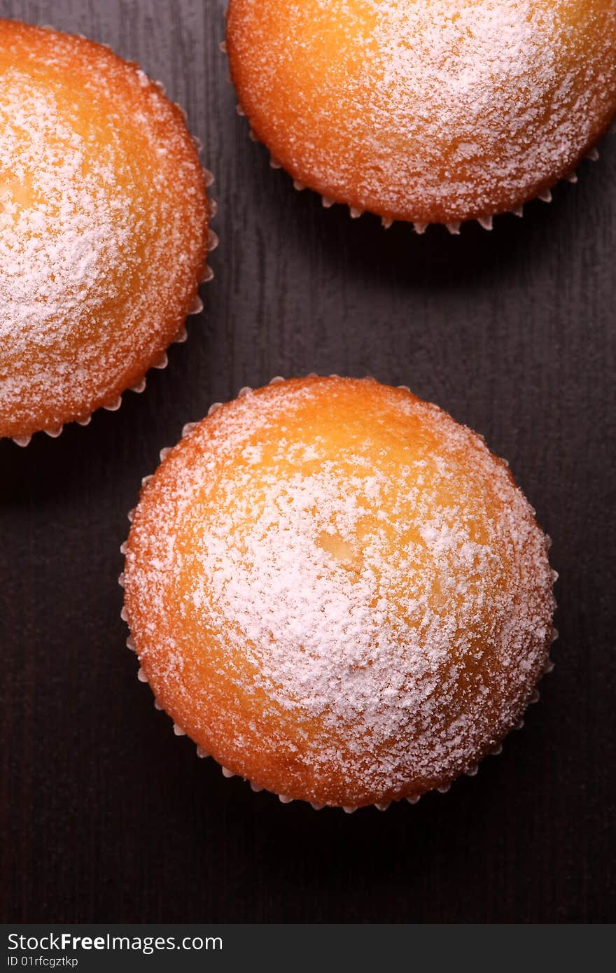 Muffins with sugar powder isolated on black surface