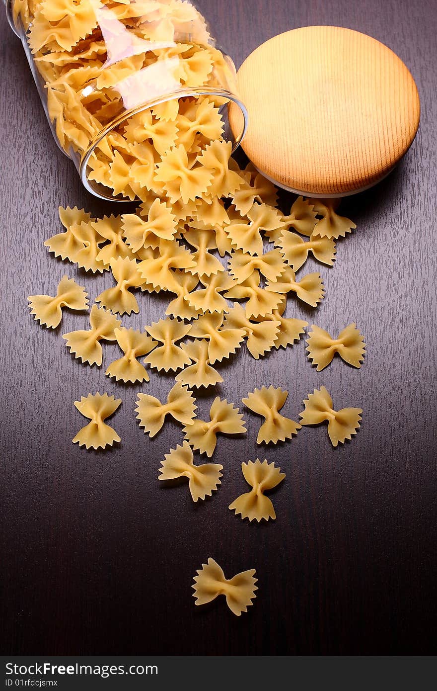 Farfalle pasta with glass isolated on black surface