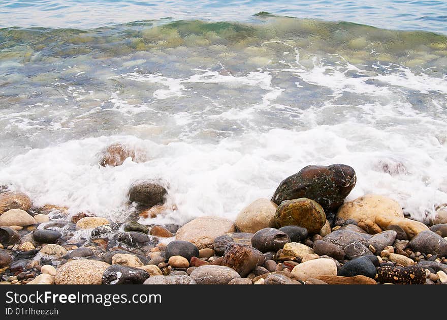 Sea foam and pebble in the water.