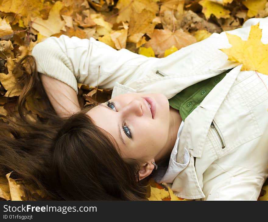 Beautiful girl lying on autumn maple leaves outdoors. Beautiful girl lying on autumn maple leaves outdoors