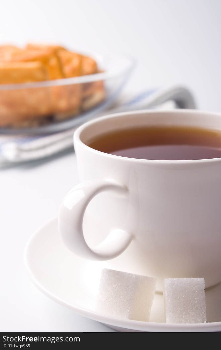 Cup of tea, sugar and cookies closeup on white