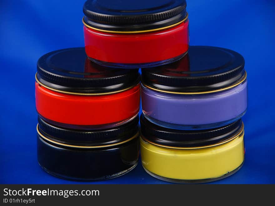 Five paint bottles of glass in different colors on a blue background. Five paint bottles of glass in different colors on a blue background