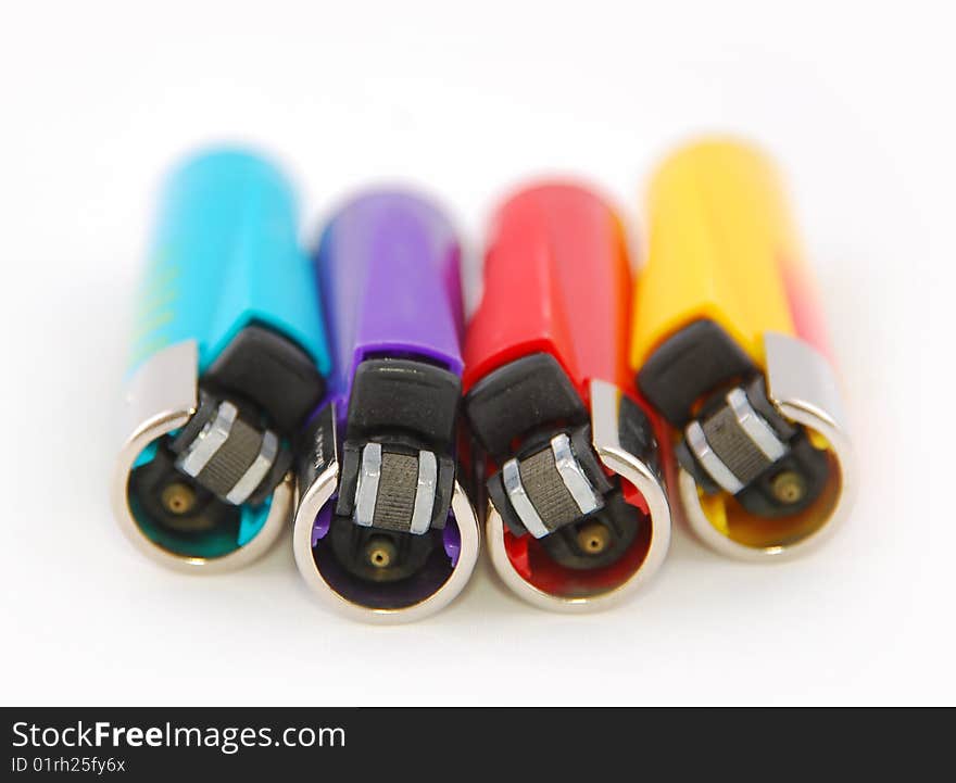 Four lighters in different colors on a white background with a shallow depht of field. Four lighters in different colors on a white background with a shallow depht of field