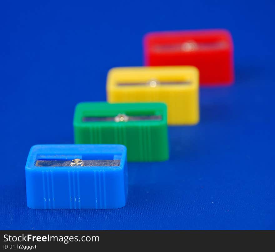 Pen sharpeners in different colors on blue background with shallow depht of field