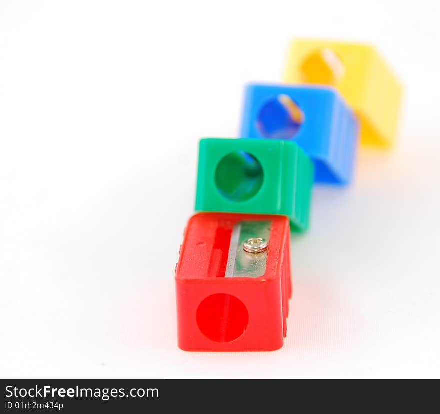 Four pen sharpeners in different colors on a white background with a shallow depht of field