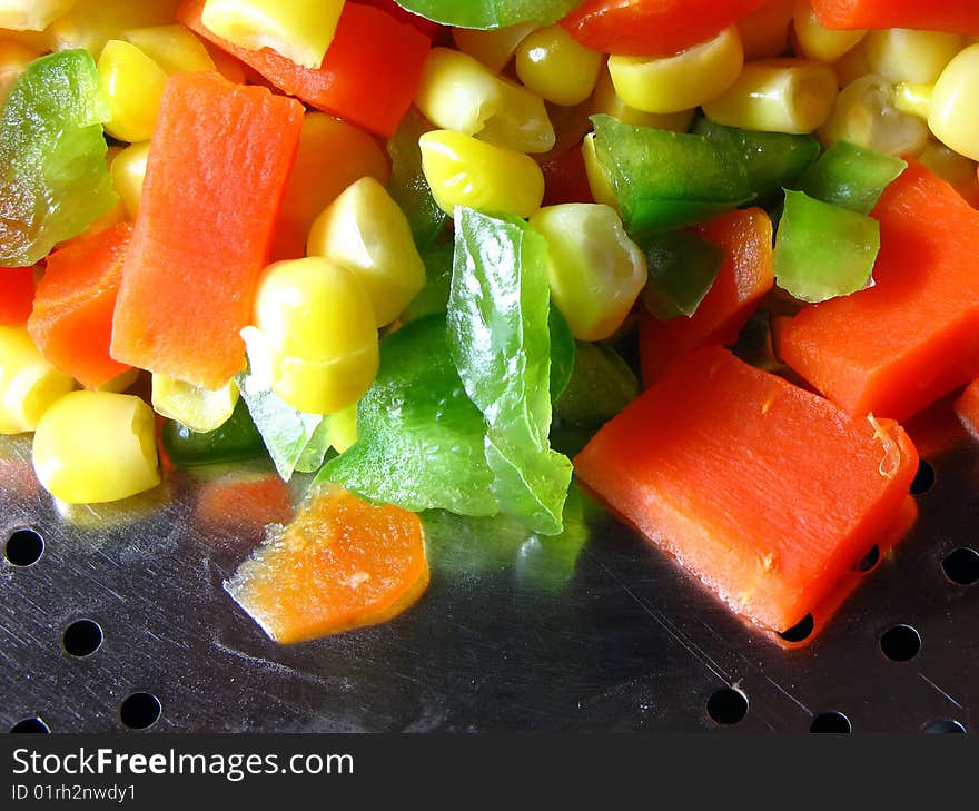 Chopped carrot and green pepper with corn seeds in strainer. Chopped carrot and green pepper with corn seeds in strainer