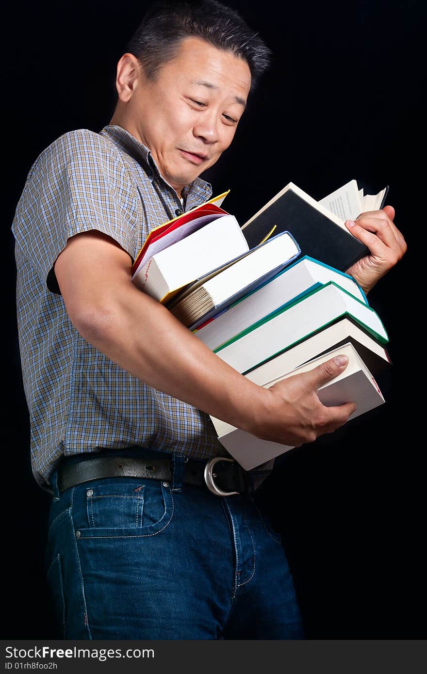 An asian student with many books dropping them - on a dark background. An asian student with many books dropping them - on a dark background.